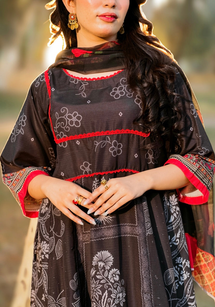 A woman wearing a black traditional embroidered dress with red and white floral patterns, a matching dupatta, and patterned red and black sleeve cuffs, photographed outdoors in warm golden light.