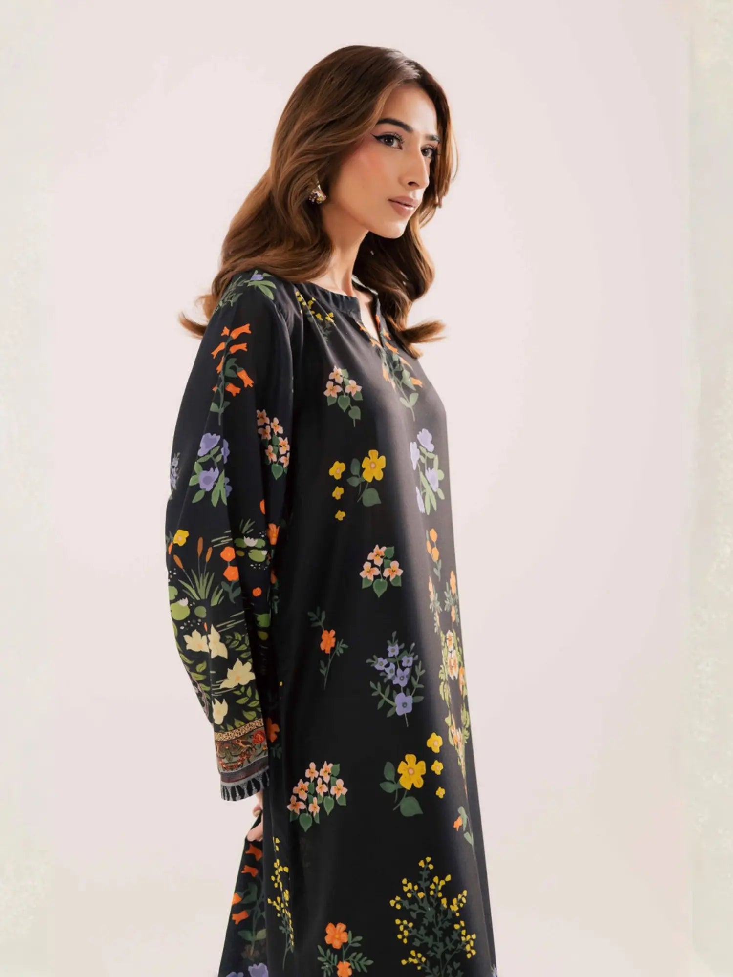 Woman wearing a black dress with colorful floral embroidery on a white background