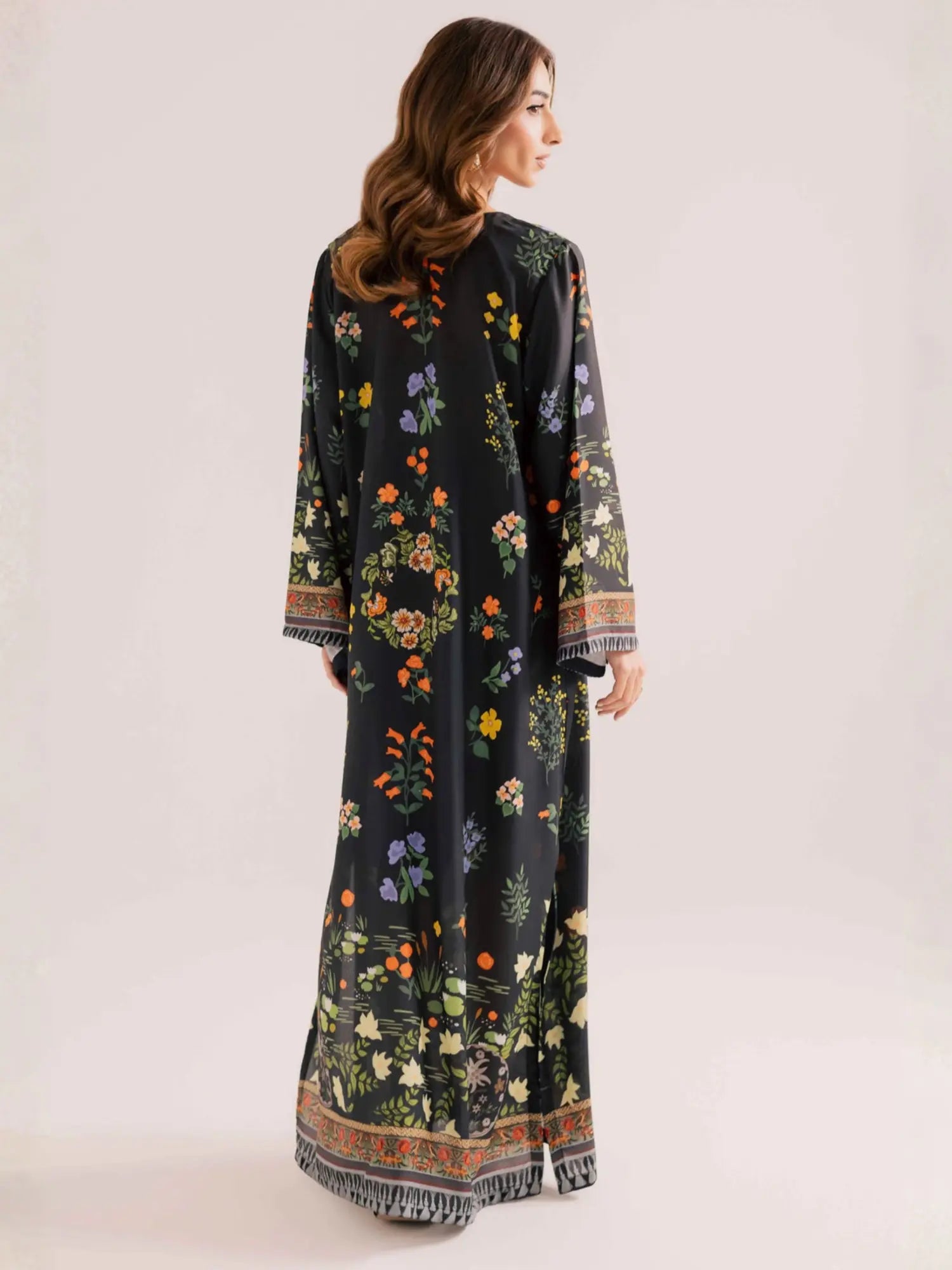 Woman wearing a long floral dress with a plain background