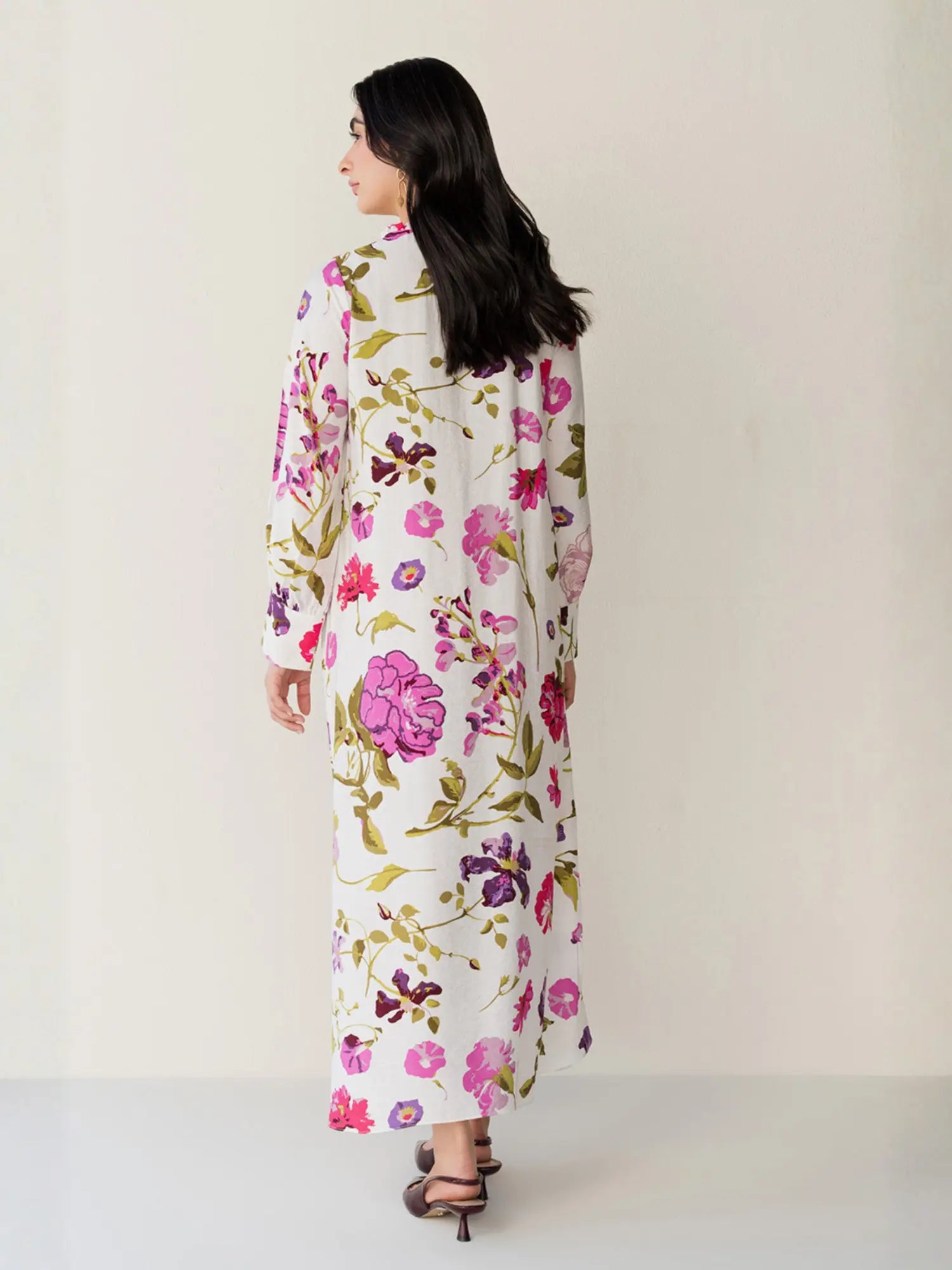 Woman wearing a long floral dress against a plain background