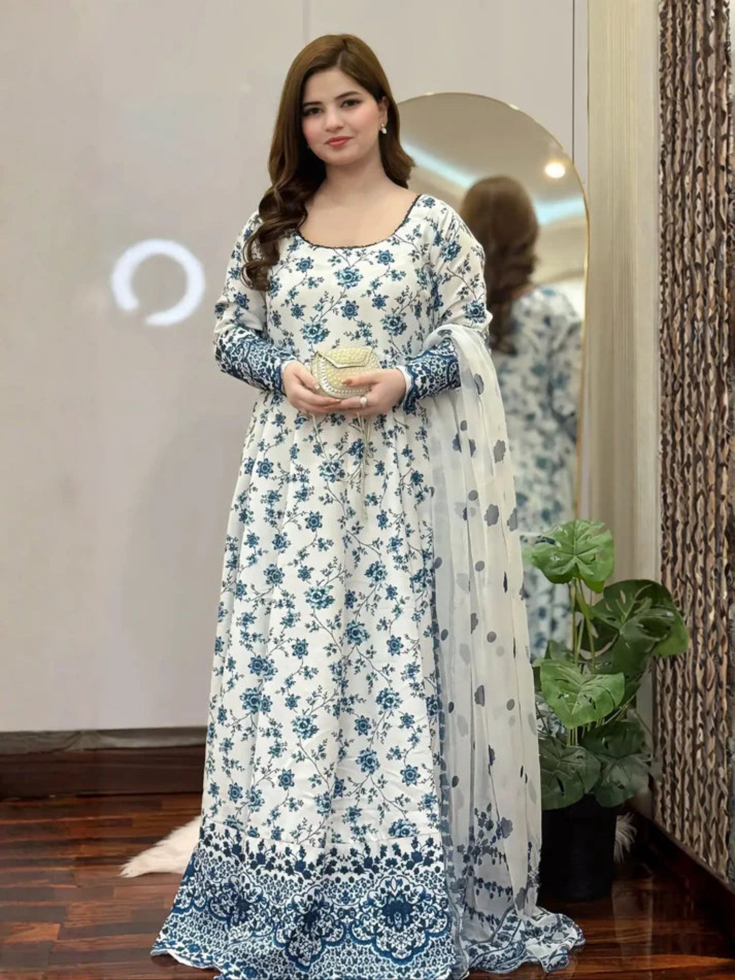 Woman in a white and blue floral dress standing in front of a mirror.