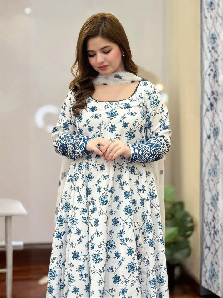 Woman wearing a white dress with blue floral patterns in an indoor setting.