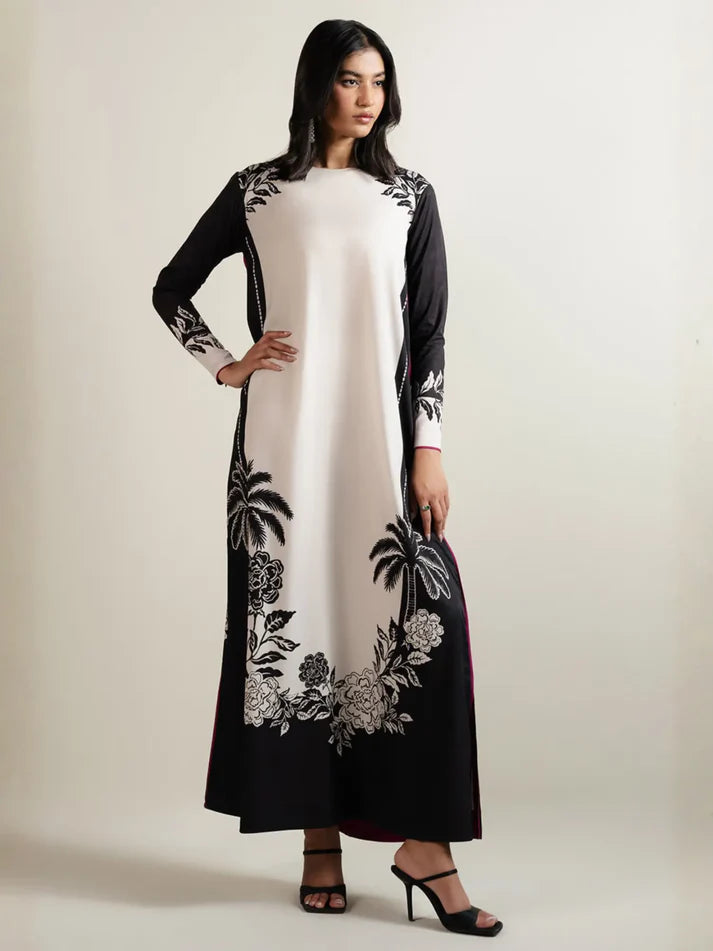 Woman wearing a black and white embroidered dress on a plain background