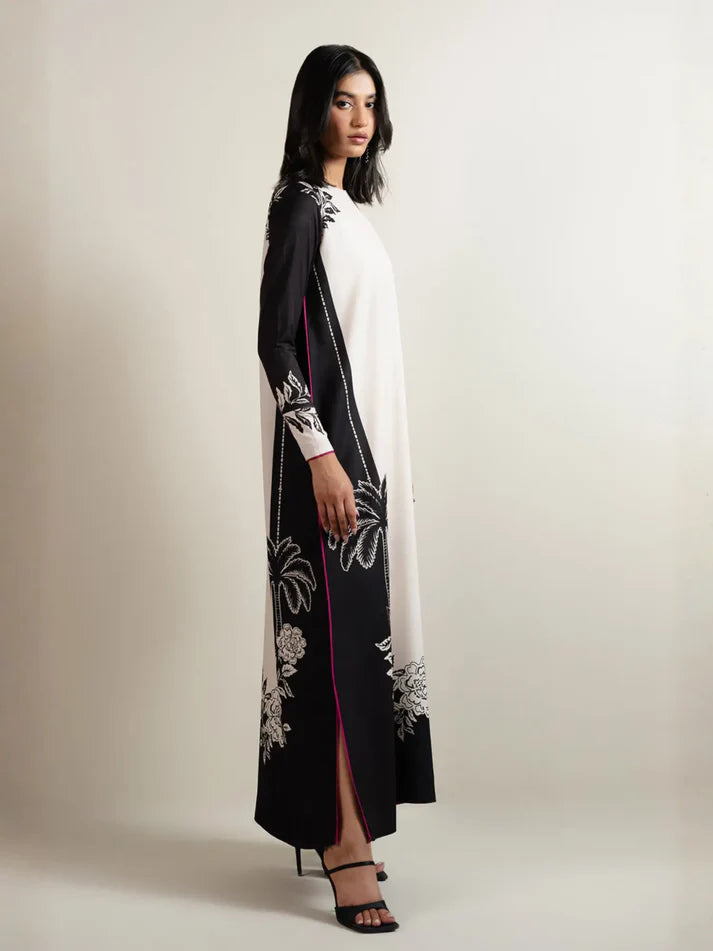 Woman wearing a black and white floral embroidered dress on a plain background