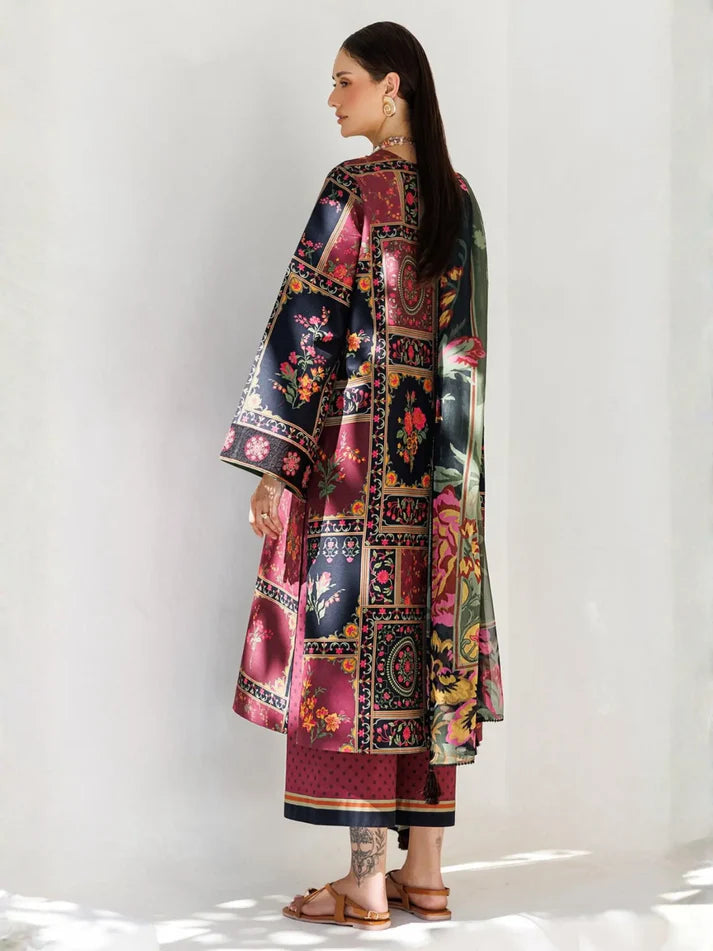 A woman modeling a three-piece printed ethnic suit, shown from the back. The outfit features a long kurta with a multicolor patchwork floral and paisley print, matching wide-leg trousers, and a coordinating sheer dupatta.