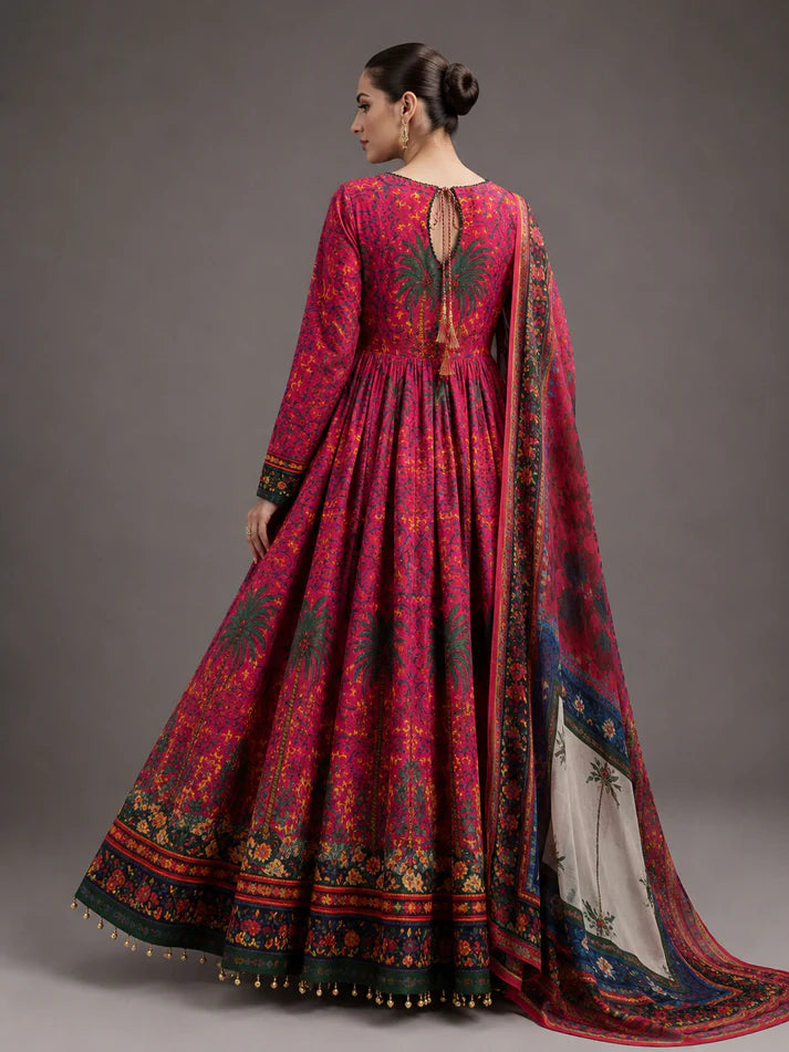 A woman modeling a traditional long magenta pink printed Anarkali gown with a matching dupatta, shown from the back against a neutral gray studio background.