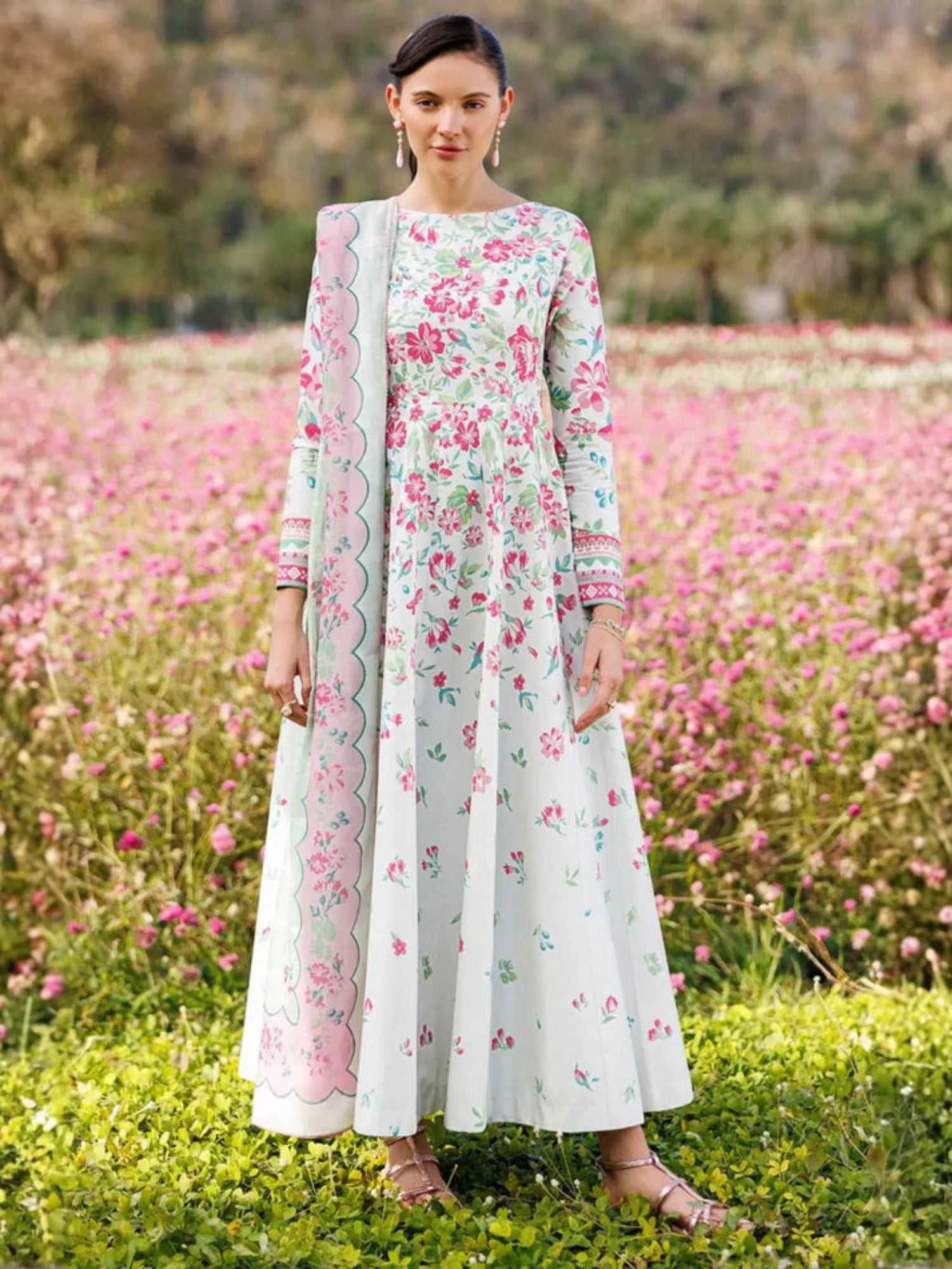 Woman in a floral dress standing in a field of pink flowers
