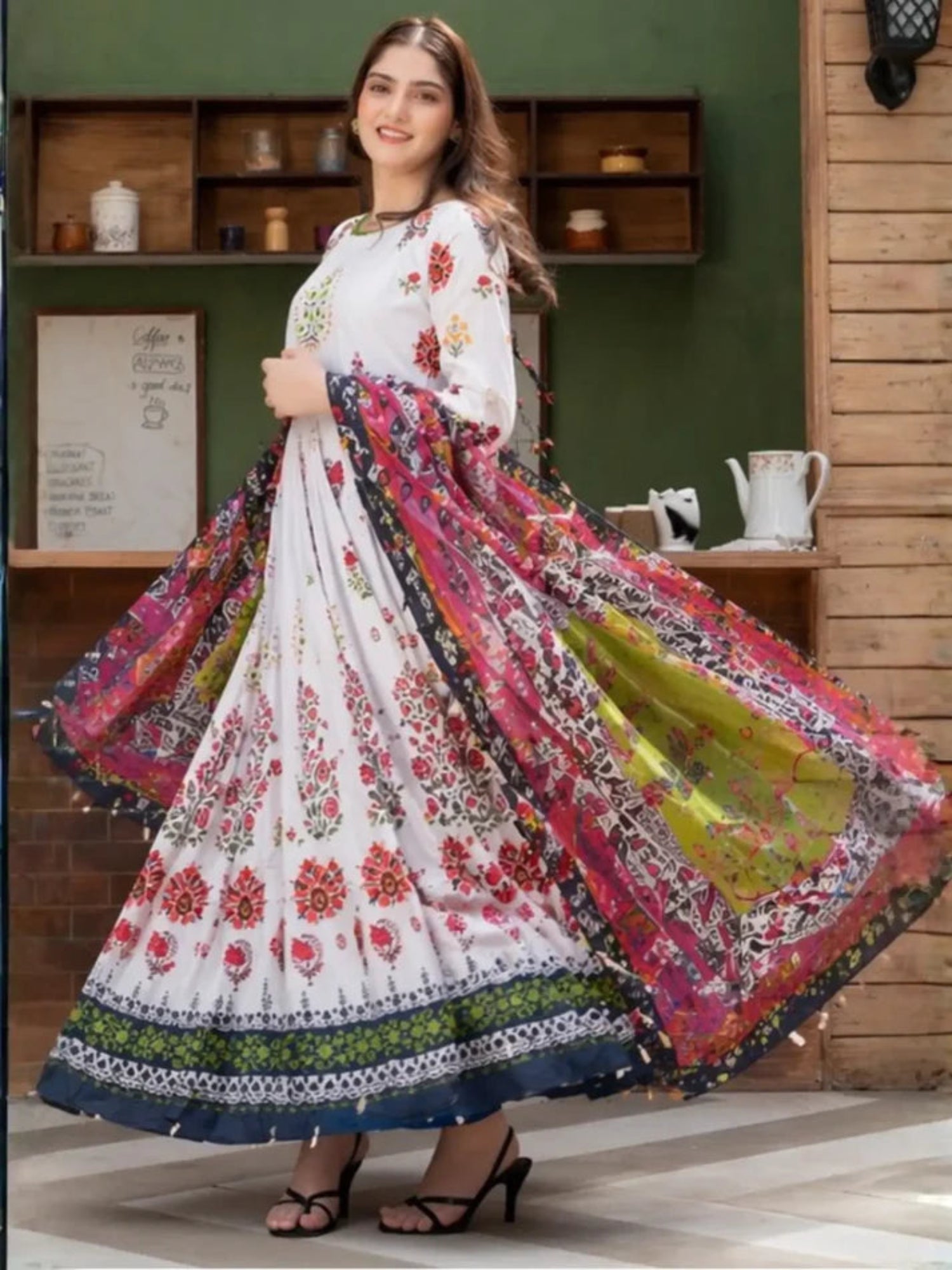 Woman wearing a colorful floral dress in a room with wooden shelves.