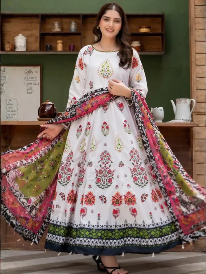 Woman wearing a white floral dress with a colorful dupatta in a room setting.
